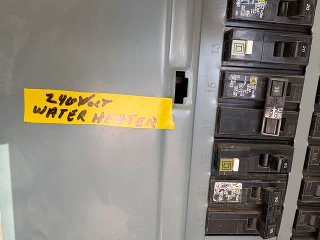 240V water heater circuit breaker in an electrical panel with handwritten label.