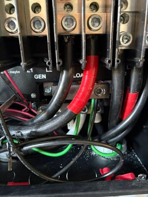 Close-up of electrical connections and wires inside a generator control panel.