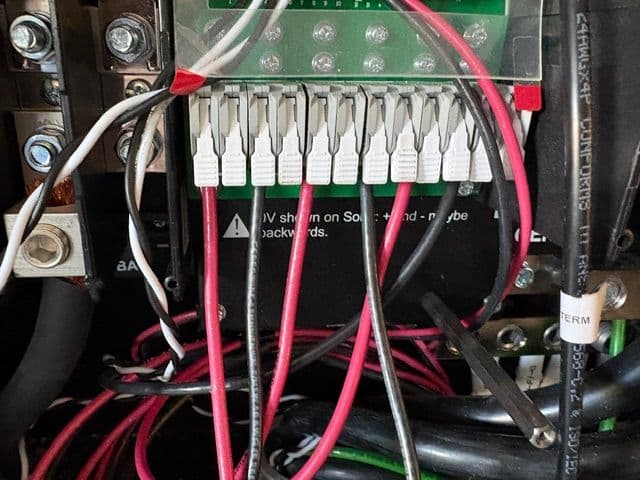 Wiring connections on a control panel with multiple colored cables and labels.