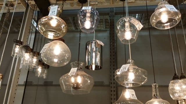 Variety of decorative pendant lights hanging from a ceiling display in a home decor store.