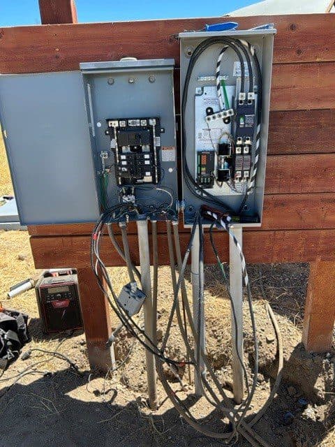 Electrical circuit panel with wires and connections mounted on a wooden structure.