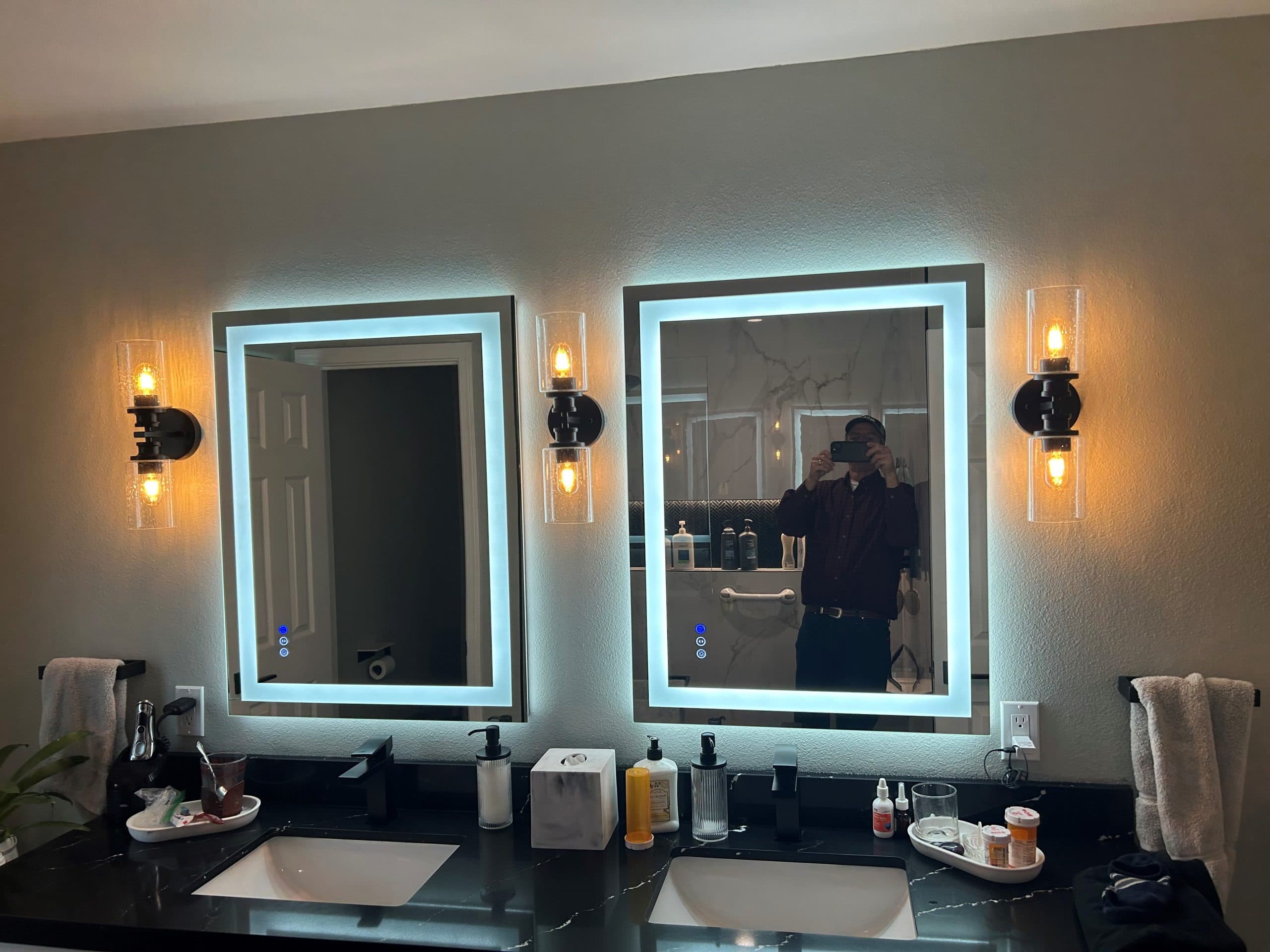 Modern bathroom with illuminated mirrors, stylish lighting, and a sleek vanity setup.